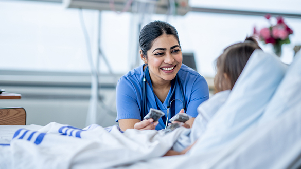 Photo of smiling nurse helping a patient in a hospital bed.